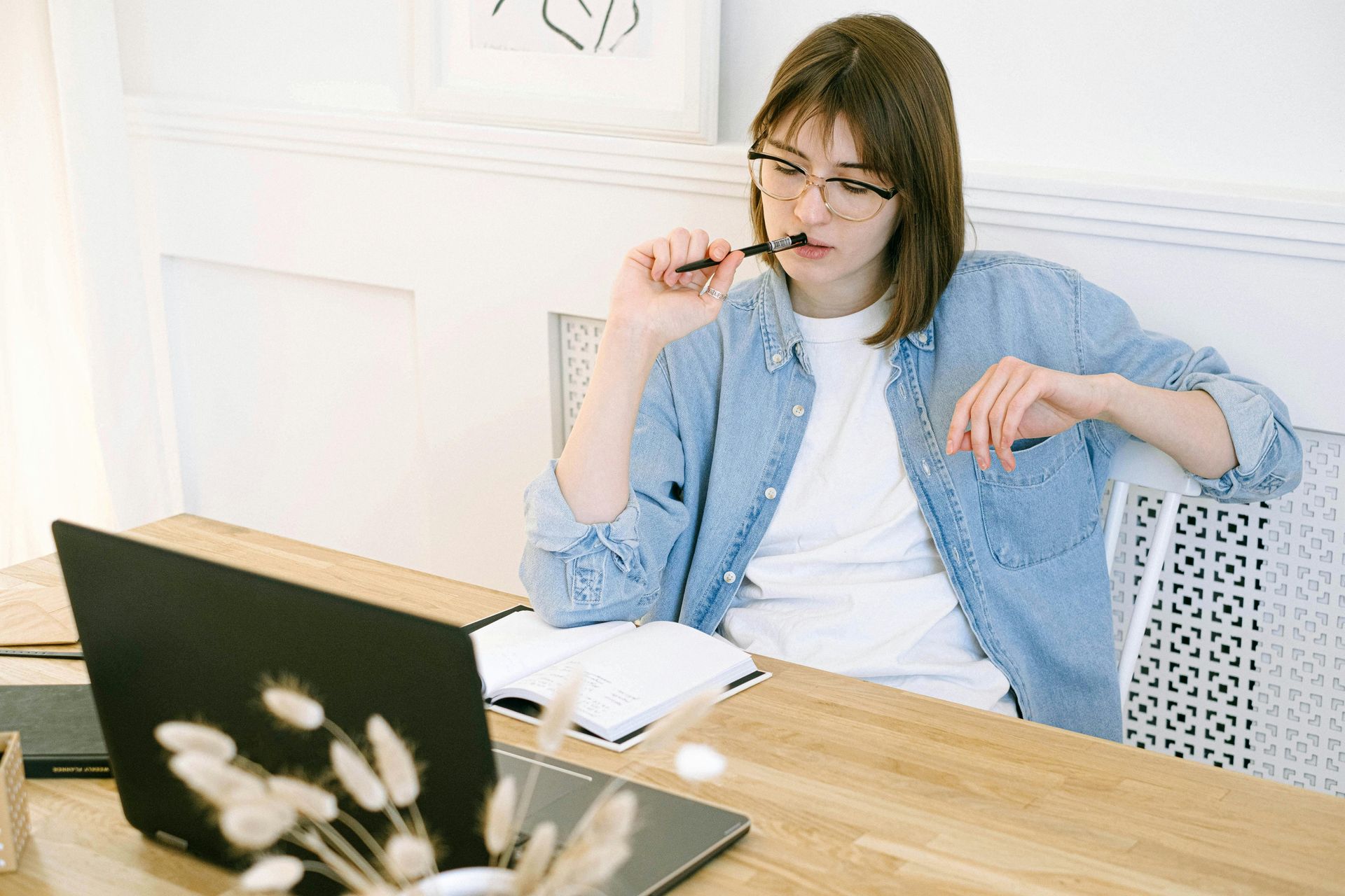 A person in deep thought, trying to write their blog with writer's block, with a notebook open and a laptop.