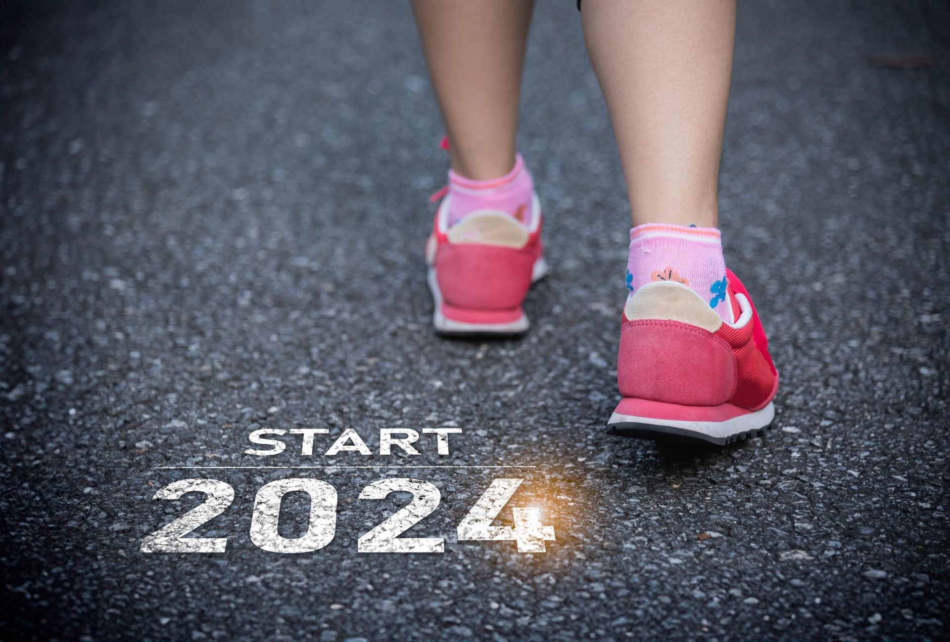 a person is walking on a road with the words `` start 2024 '' written on it .