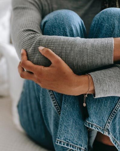 A woman is sitting on the floor with her legs crossed and her hands on her knees.