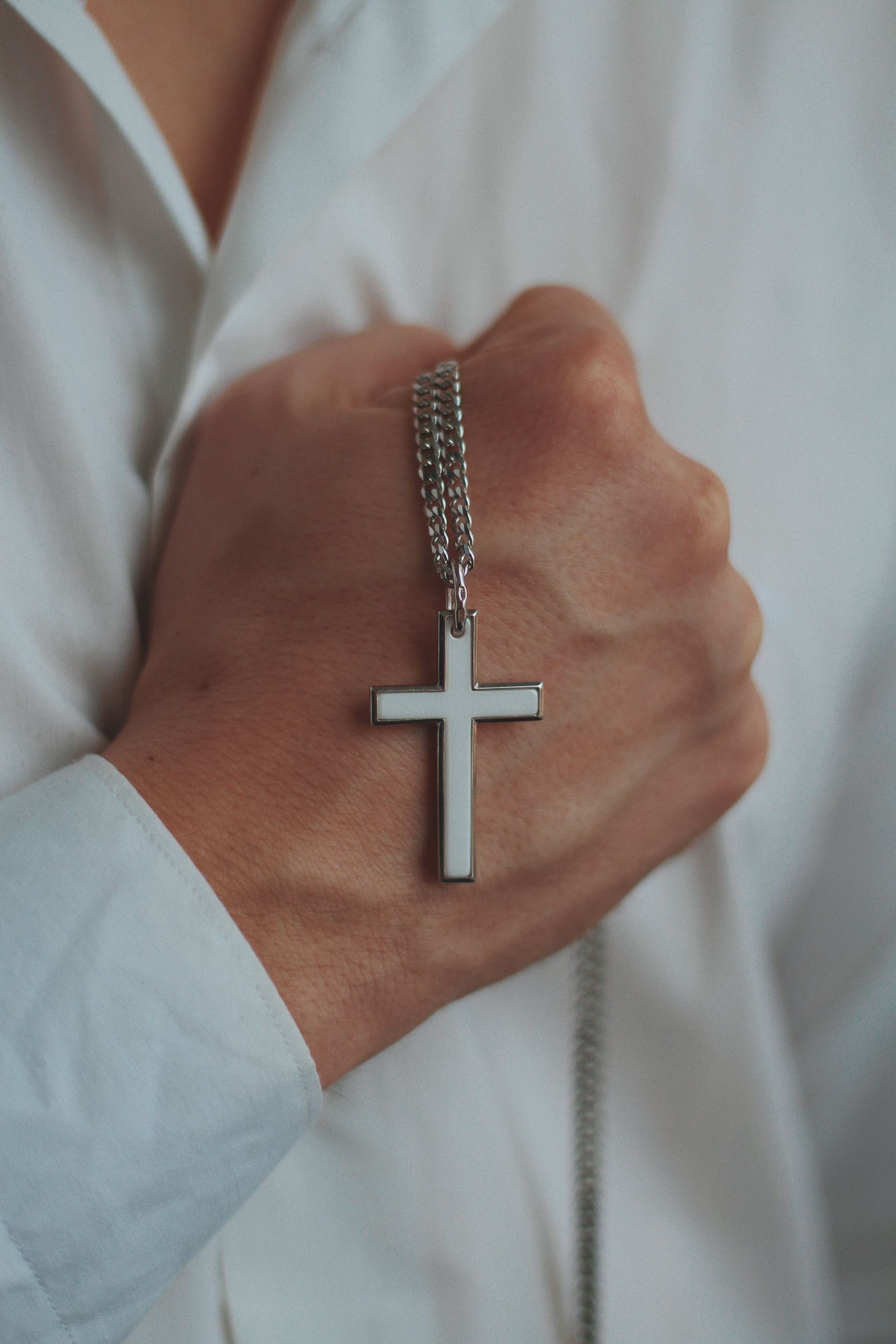 A person is wearing a cross necklace on their wrist