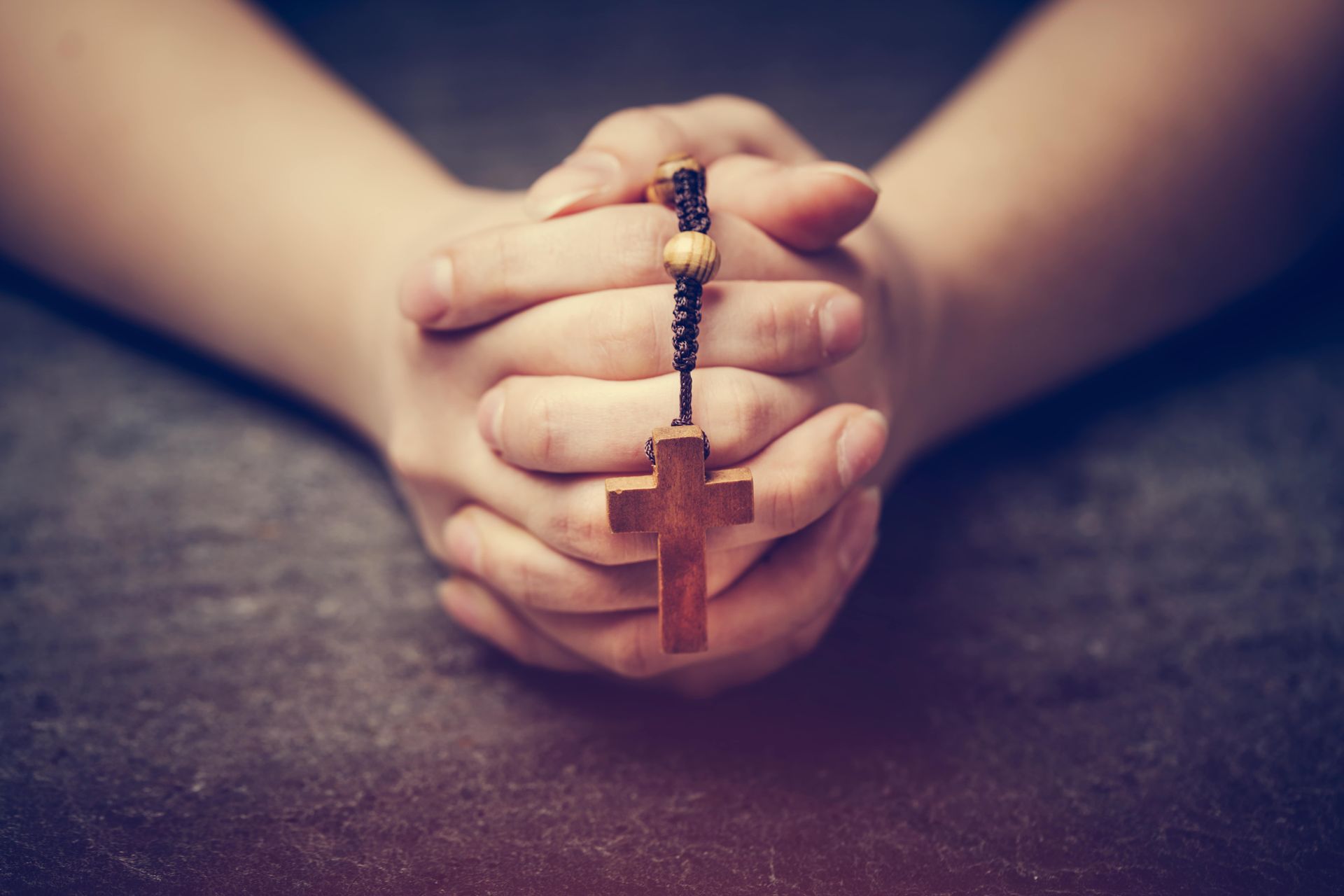 A person is praying with a rosary in their hands.