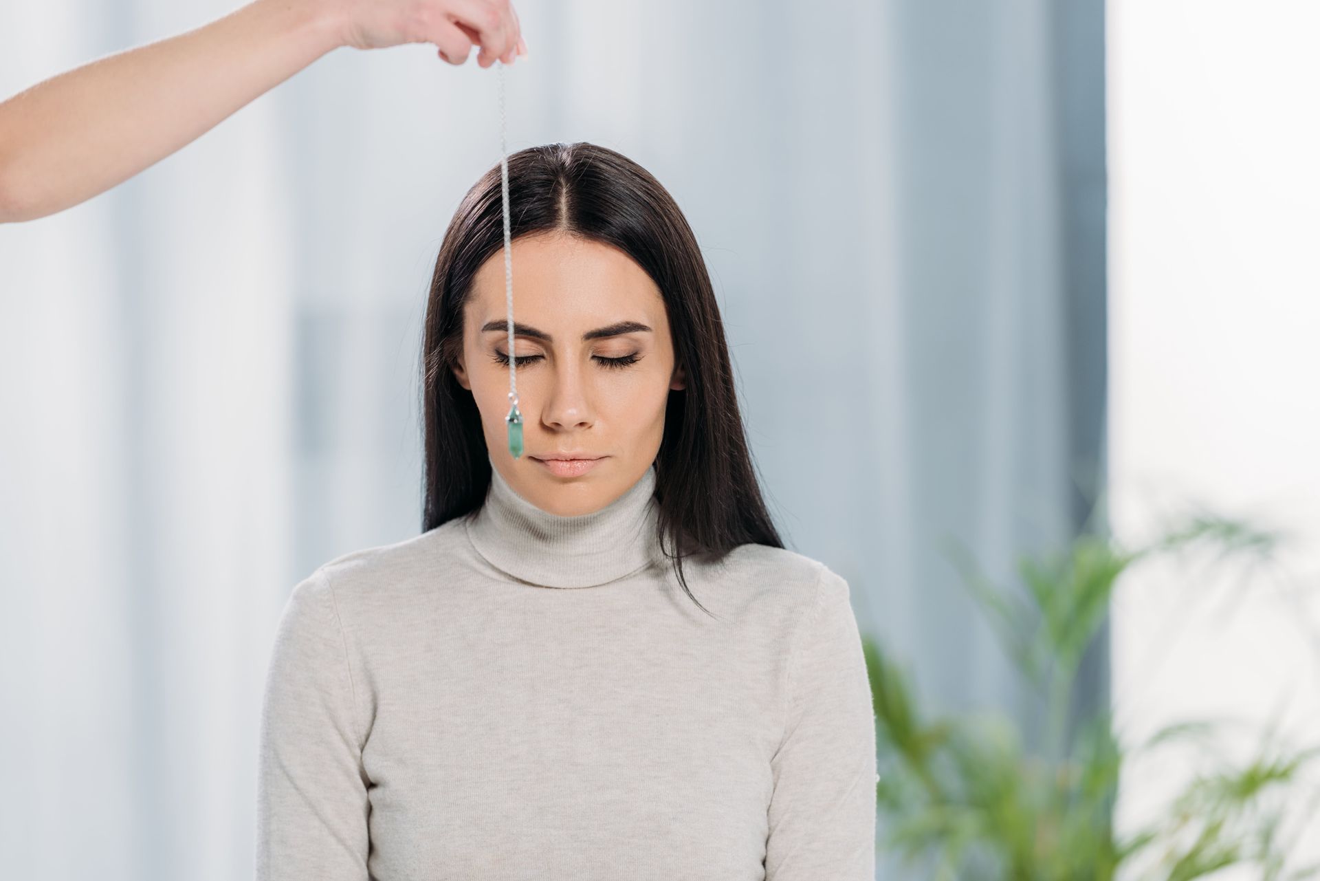 A woman is being hypnotized with a pendulum.