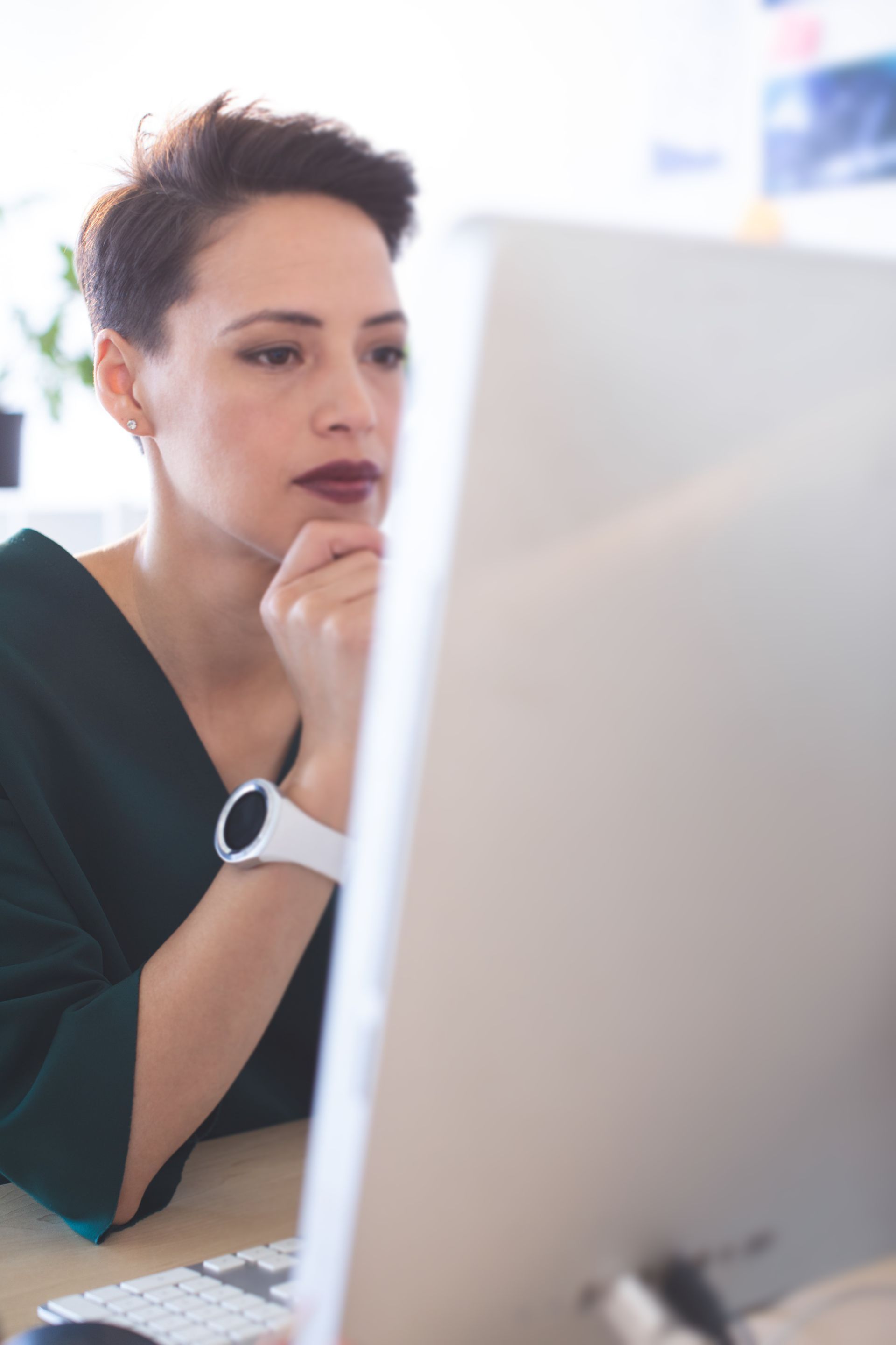 A woman is sitting at a desk looking at a computer screen.