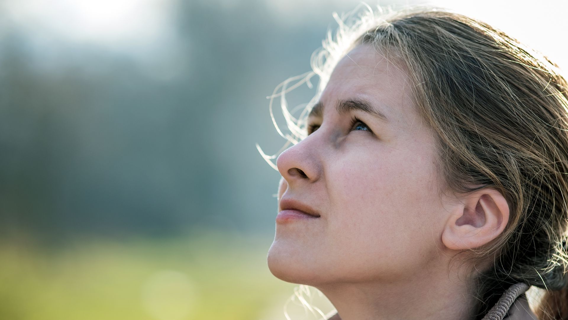 A close up of a woman 's face looking up at the sky.