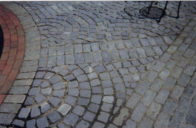A cobblestone walkway with a circular design in the middle