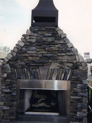 A stone fireplace with a stainless steel surround and a mailbox on top.
