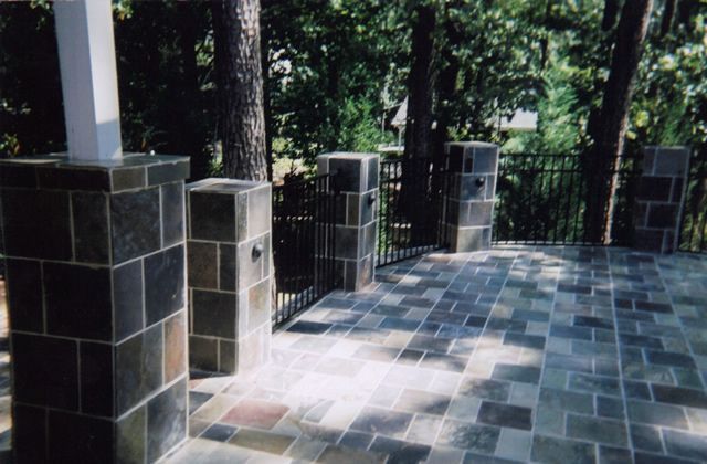 A stone patio with columns and trees in the background