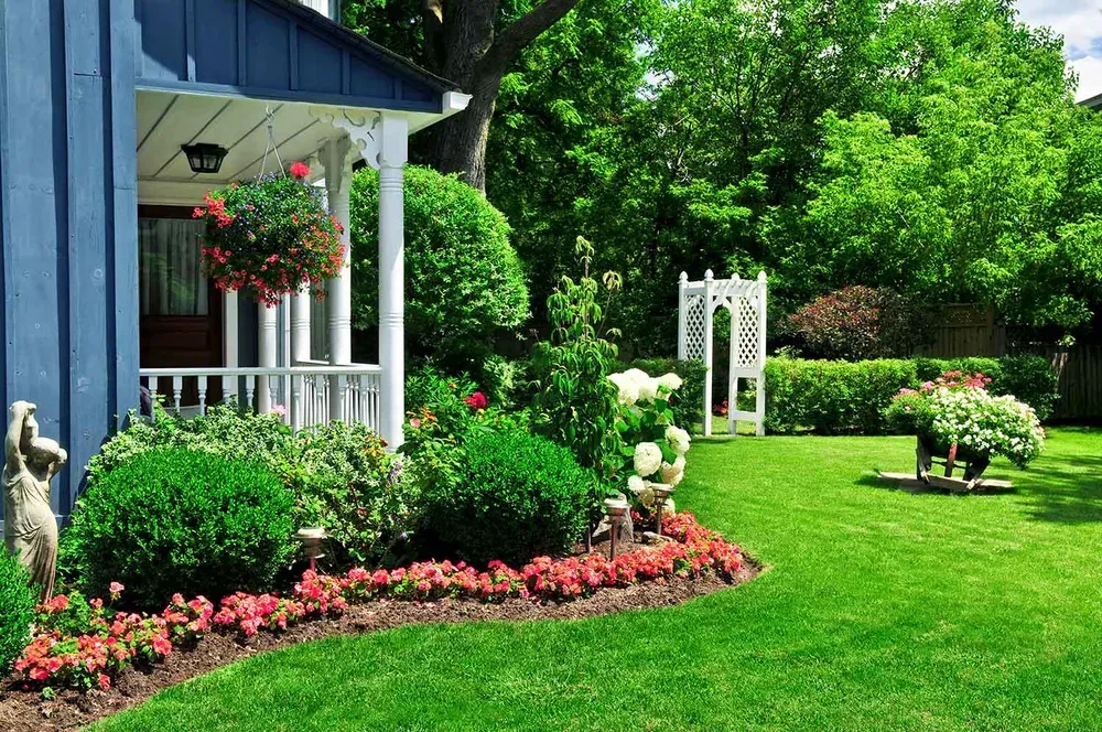 A house with a large lawn and flowers in front of it