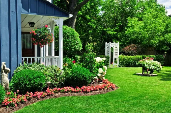 A house with a large lawn and flowers in front of it
