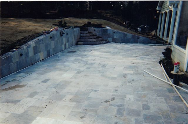 A patio with a staircase leading up to a swimming pool