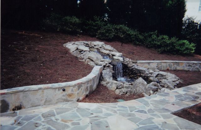 A small waterfall is surrounded by a stone wall