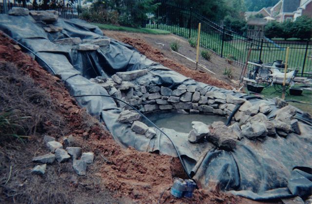 A pond is being built in the backyard of a house.