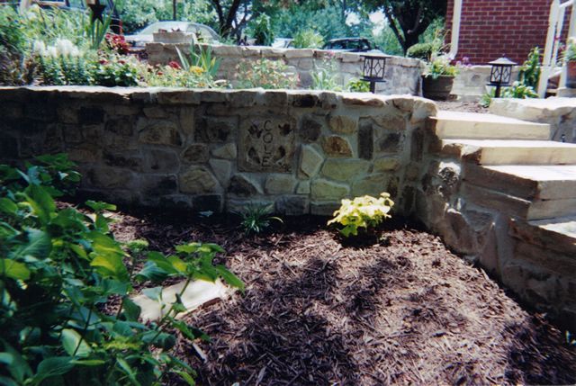 A stone wall with stairs leading up to a house