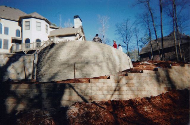 A group of people standing on top of a concrete wall in front of a large house.