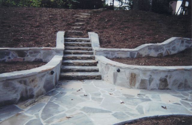 A stone walkway with stairs leading up to a hill.