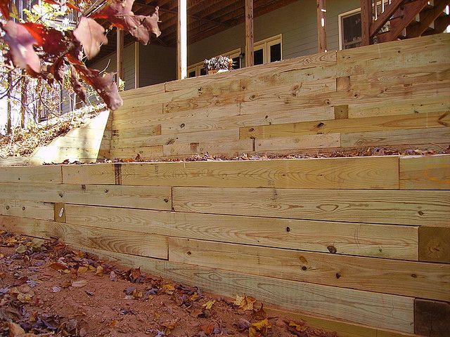 A wooden retaining wall is being built in front of a house.