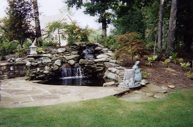 A waterfall in a garden with a statue in the foreground