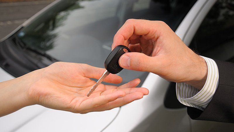 person handing car keys to someone else