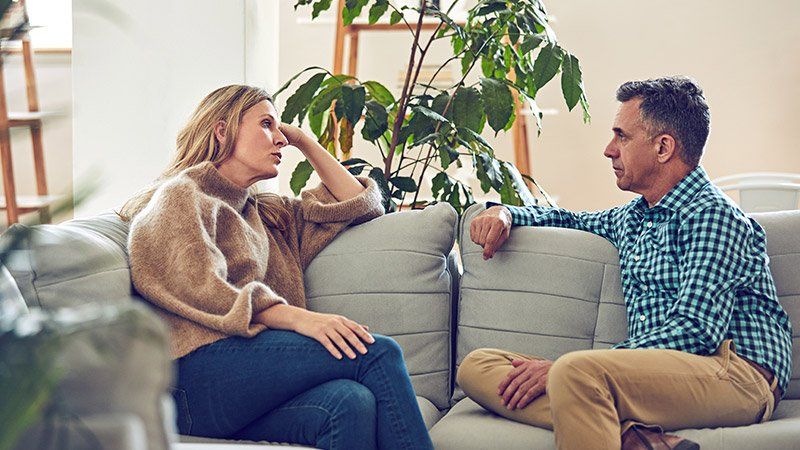 man and woman talking on a couch