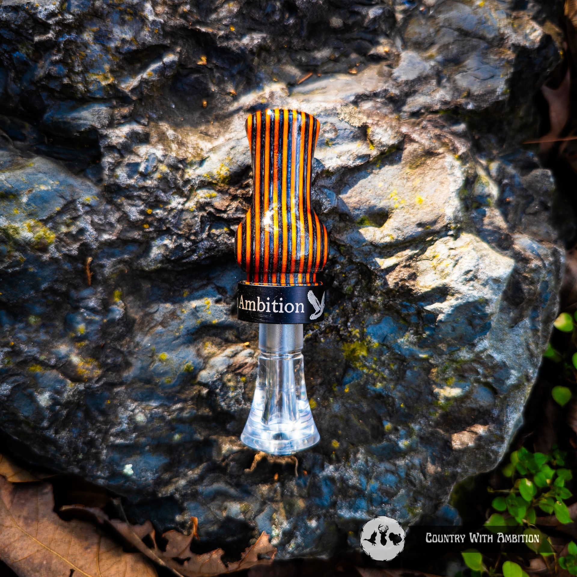 Blue hand turned duck call on a rough, blue-gray rock. Blue Country With Ambition band.