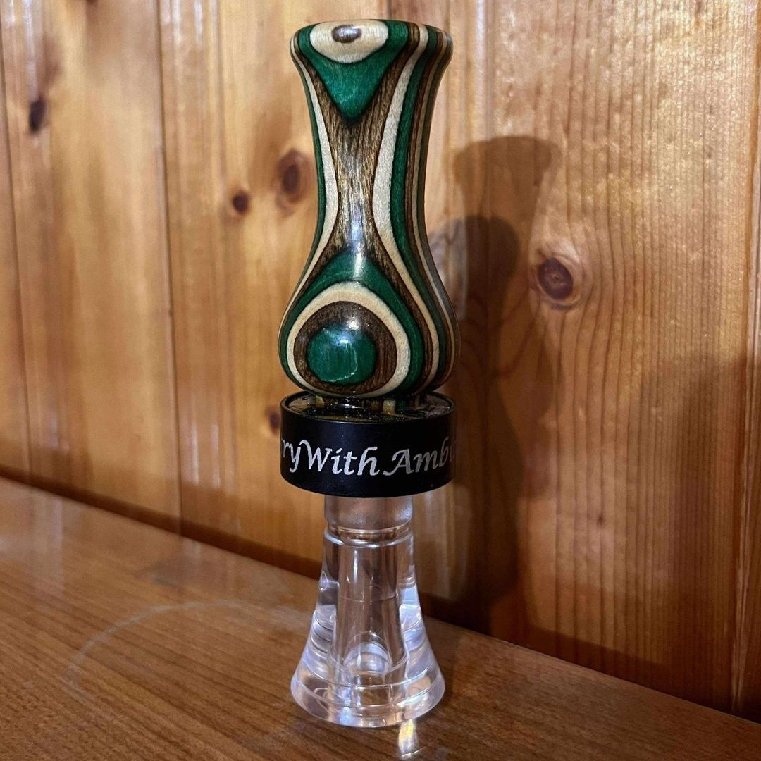 Green hand turned duck call on a rough, blue-gray rock. Black Country With Ambition band.