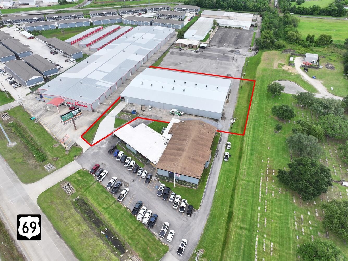 Aerial view of a commercial property with buildings, parking, and a green lawn near highway 69.