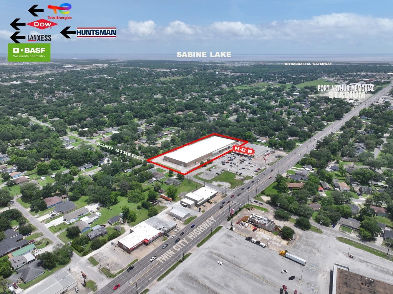 Aerial view of a commercial building near Twin City Highway, with street signs and a lake in the distance.