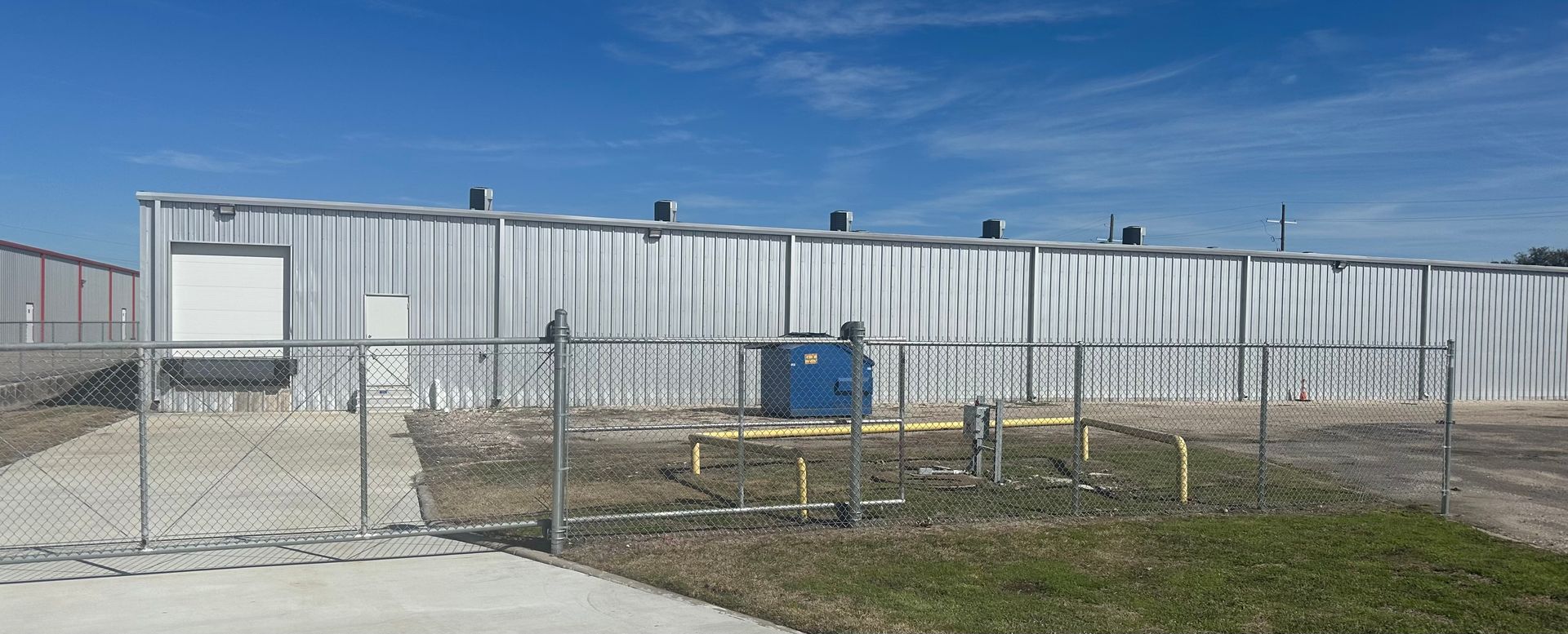 A large building is behind a chain link fence.