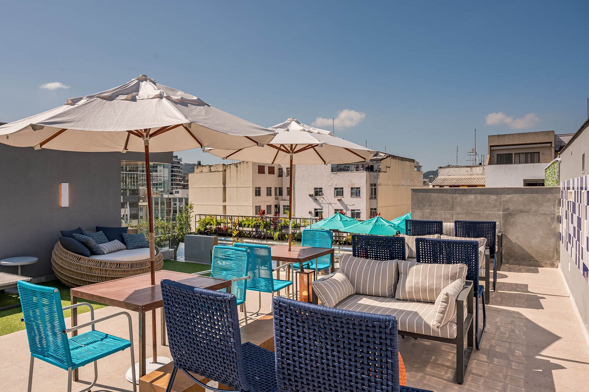 Um pátio na cobertura com muitos móveis e guarda-sóis