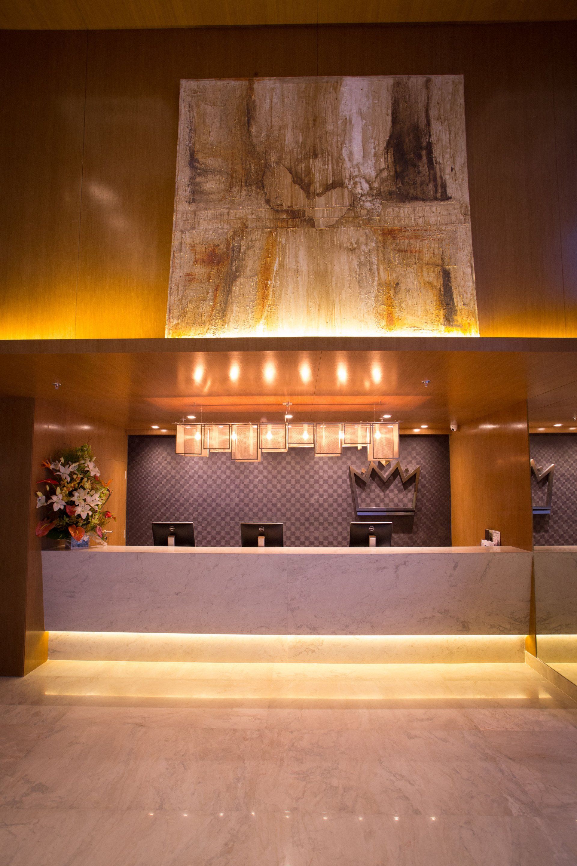 Um lobby de hotel com uma recepção e uma pintura na parede.