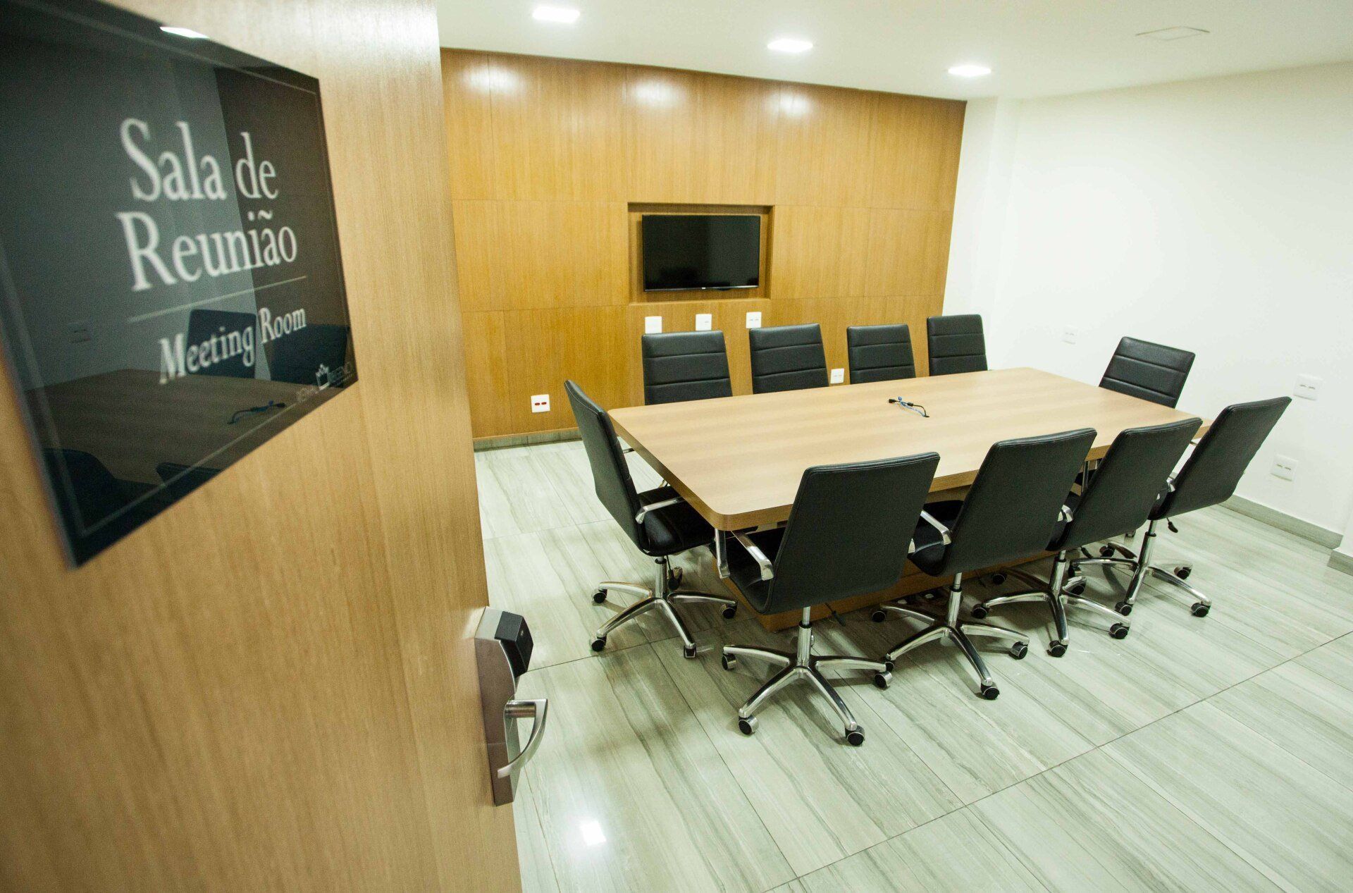 Uma sala de conferências com uma mesa e cadeiras e uma placa que diz sala de reunião sala de reunião