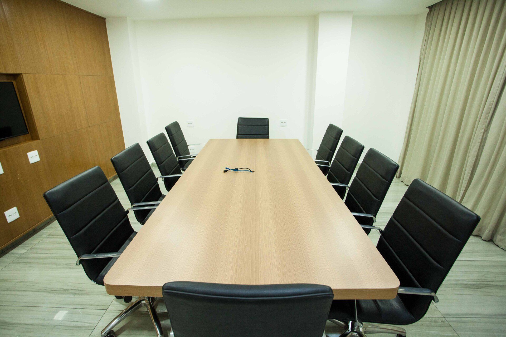 Uma sala de conferências com uma longa mesa de madeira e cadeiras pretas.
