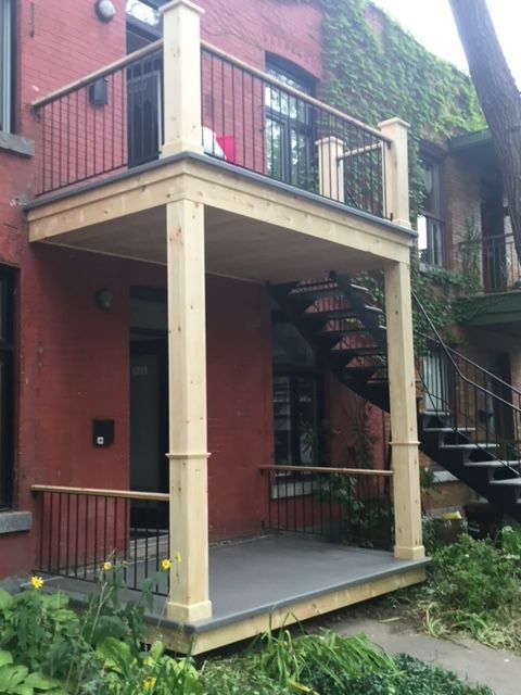 Une maison rouge avec un porche et des escaliers en bois