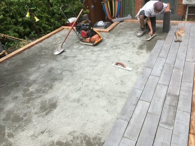 Un homme pose du béton sur un patio avec une truelle.
