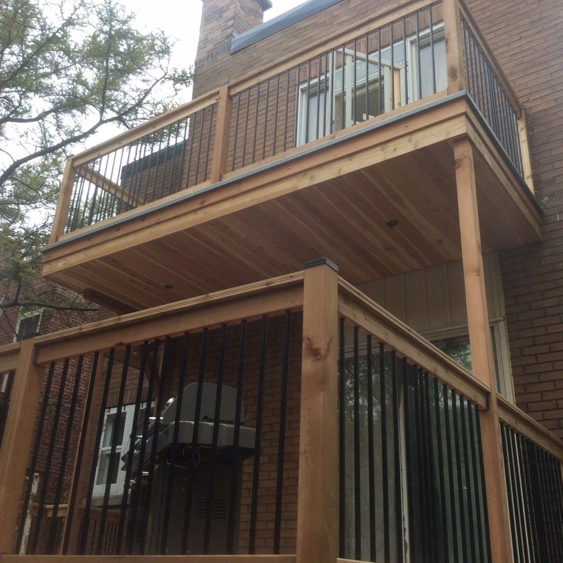 Un balcon en bois avec une balustrade en métal sur un bâtiment en brique