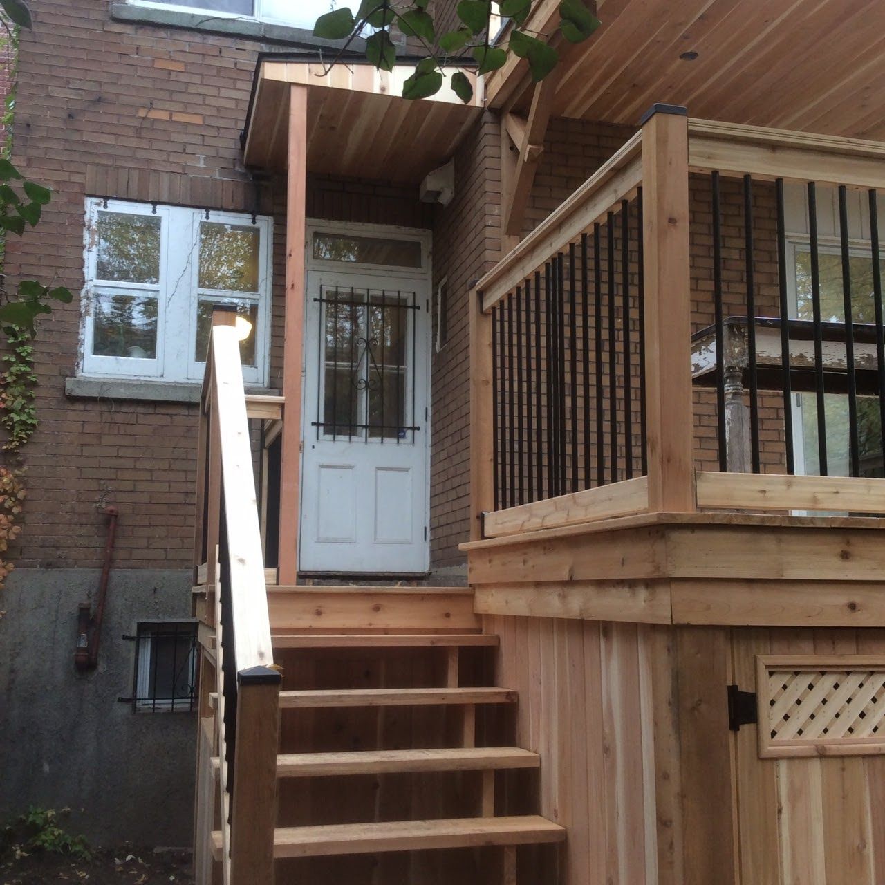 Un porche en bois avec des escaliers menant à une porte blanche