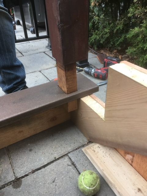 Une balle de tennis est posée sur le sol à côté d'un morceau de bois.