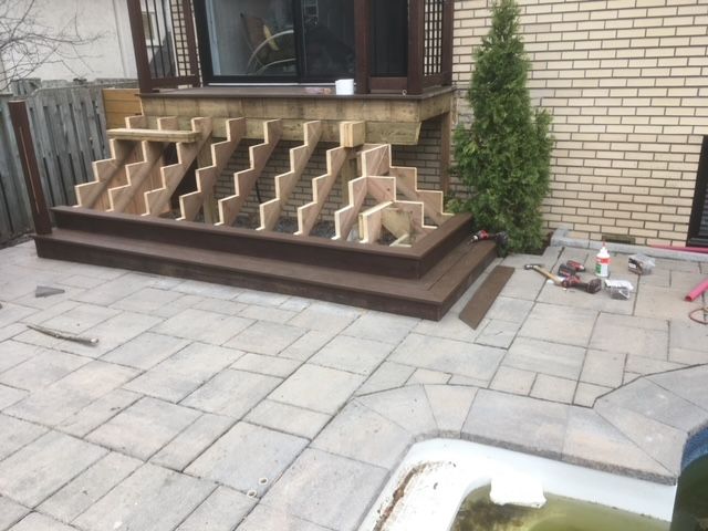 Une terrasse en bois est en cours de construction devant une maison en briques