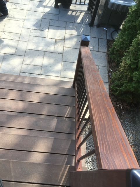 Une terrasse en bois avec des escaliers et une balustrade en métal