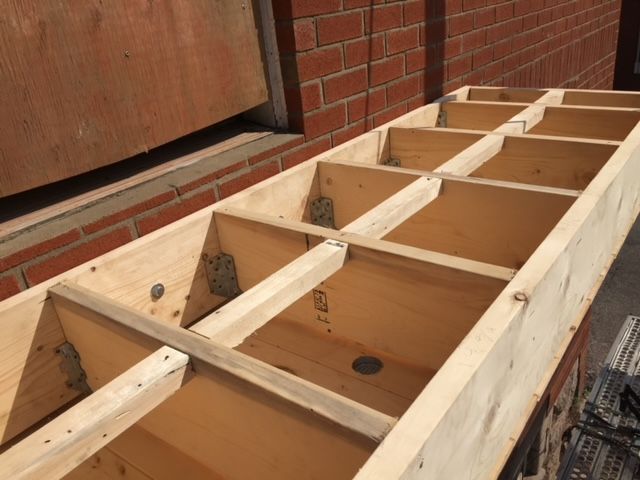 Une étagère en bois est en cours de construction devant un mur de briques