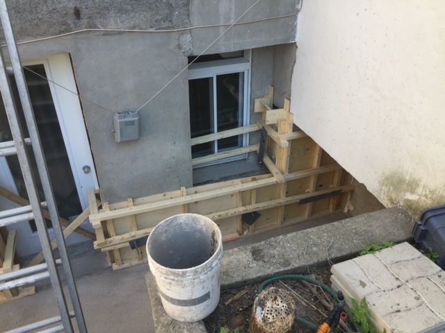 Un seau de ciment se trouve devant un bâtiment en construction
