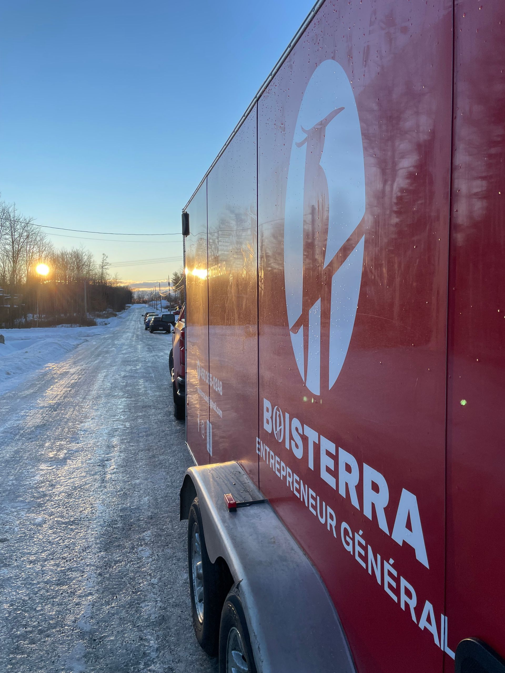 Un camion rouge est garé sur le bord d'une route enneigée.