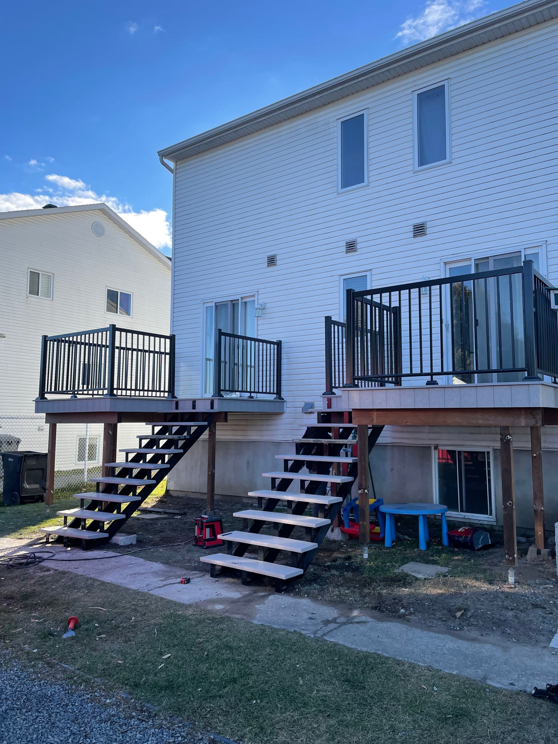 Une maison blanche avec une terrasse et des escaliers devant.