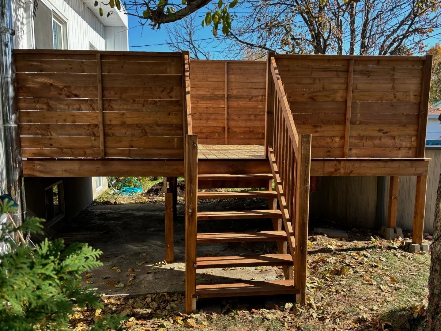 Une terrasse en bois avec des escaliers qui y mènent se trouve dans l'arrière-cour d'une maison.