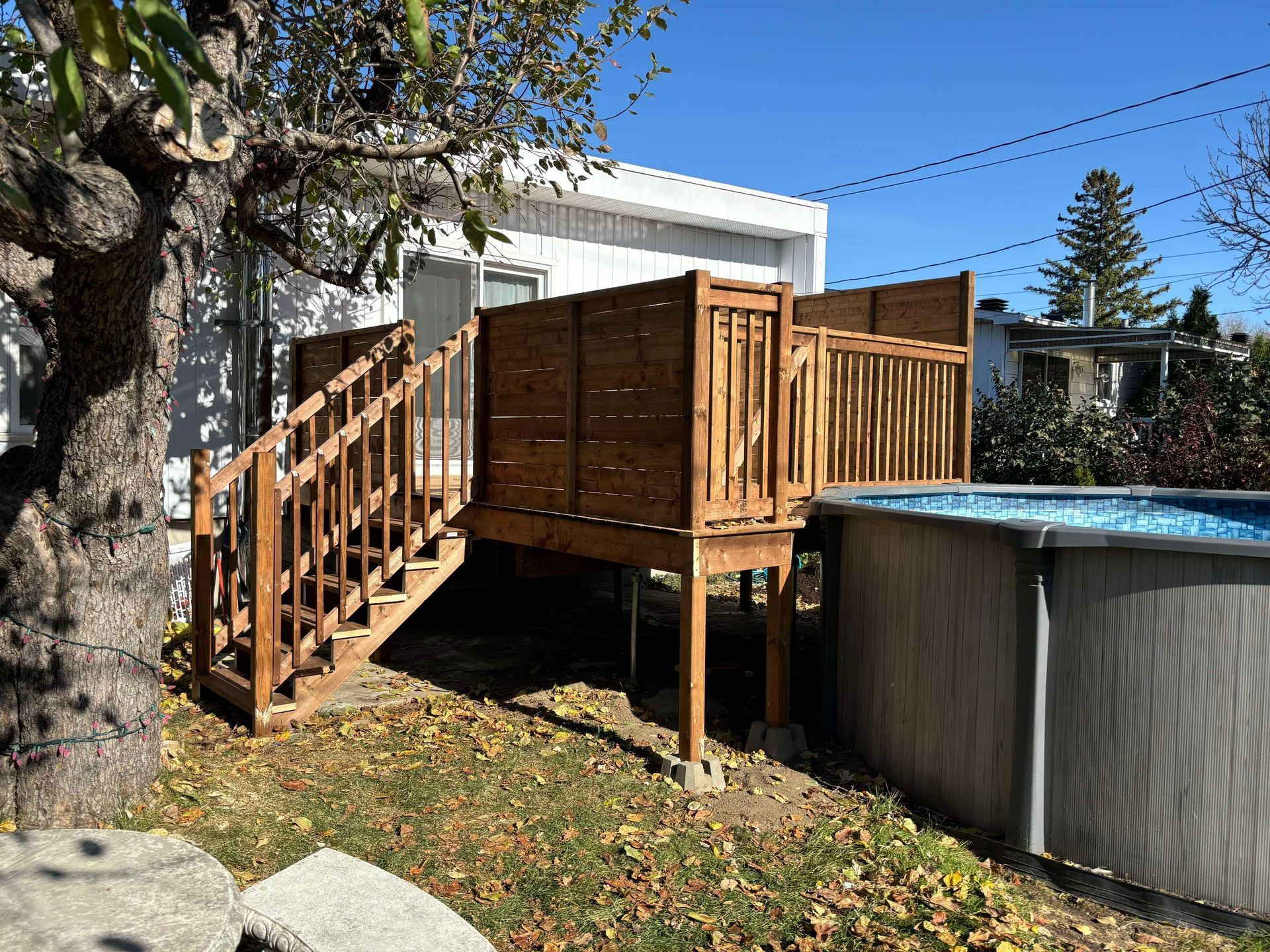 Une terrasse en bois avec des escaliers qui y mènent à côté d'une piscine.