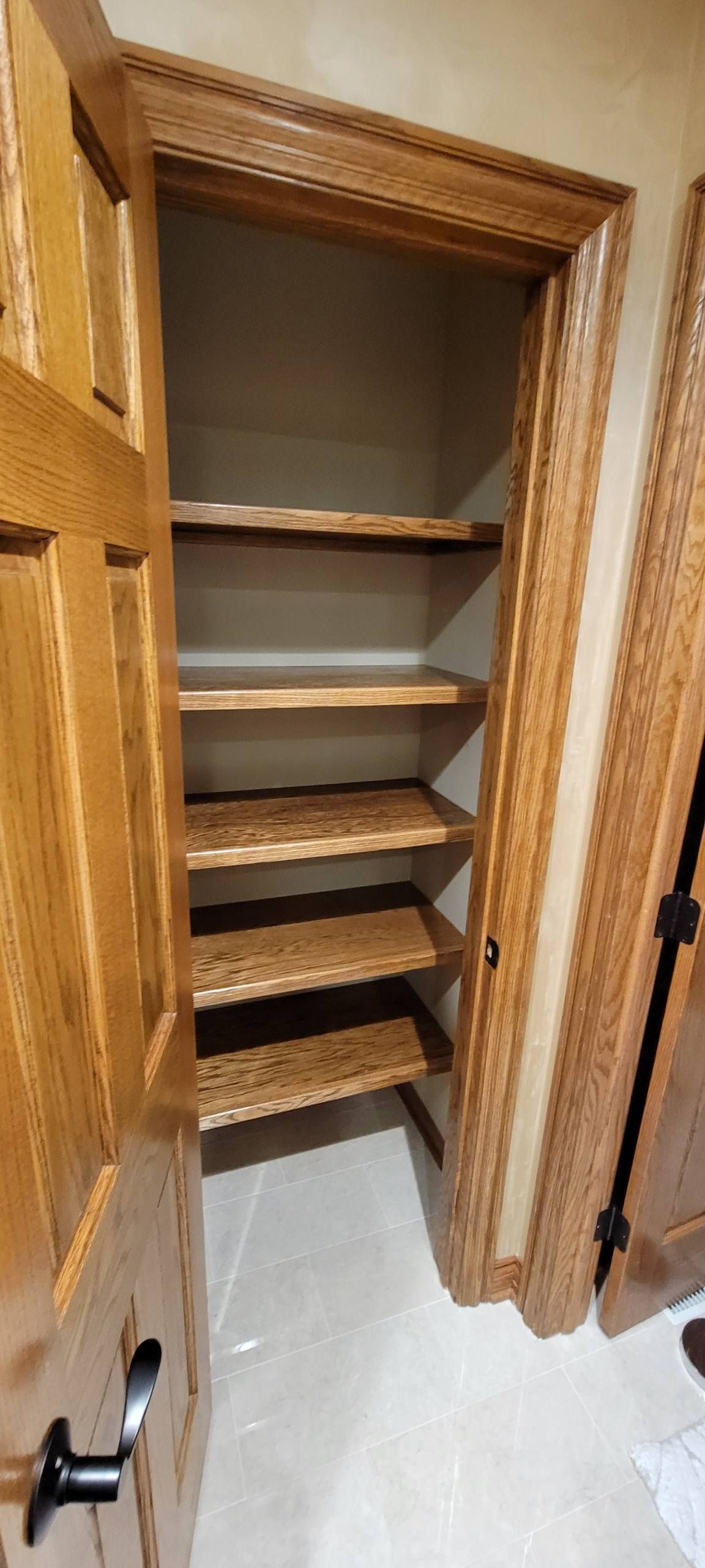 An open doorway reveals a walk-in closet featuring light oak wood shelving and matching door frames.