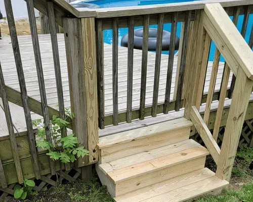New wooden steps with a railing lead up to a deck gate beside an above-ground swimming pool.