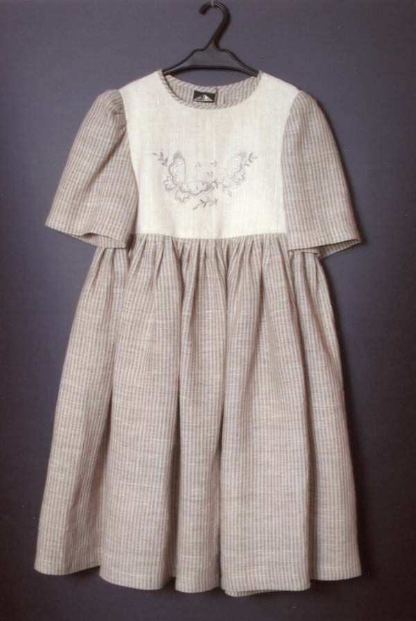 Brūna un balta lina kleita karājas uz pakaramā