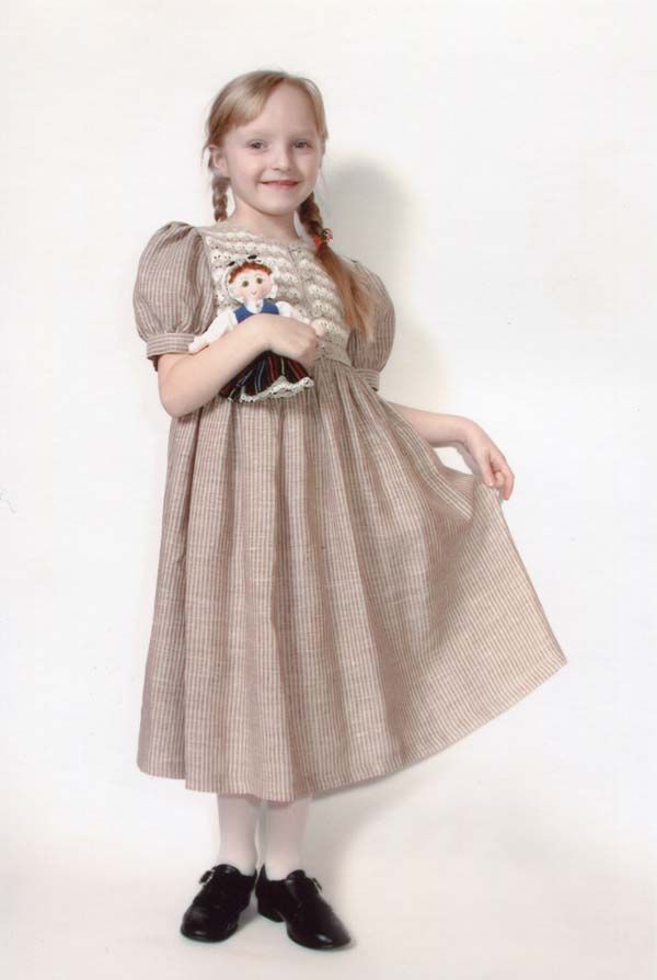 Maza meitene lina kleitā tur lelli