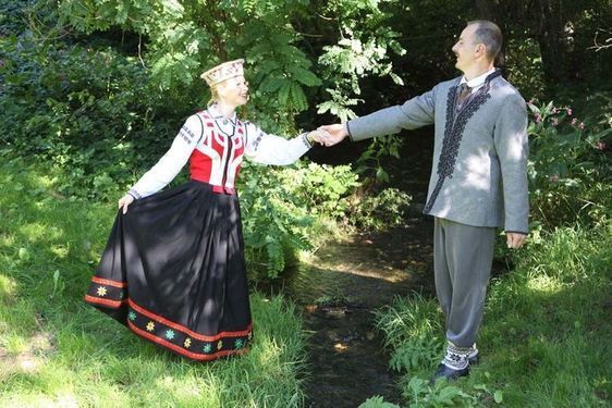 Vīrietis un sieviete dejo zālē, sadevušies rokās